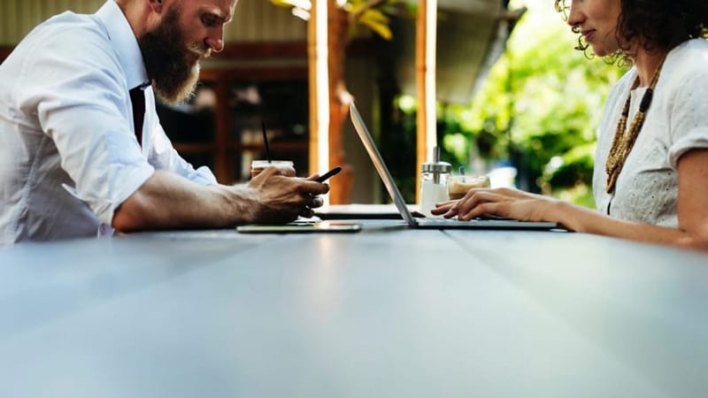 Self-employment tax advice for expats with foreign income – two professionals working on laptops outdoors